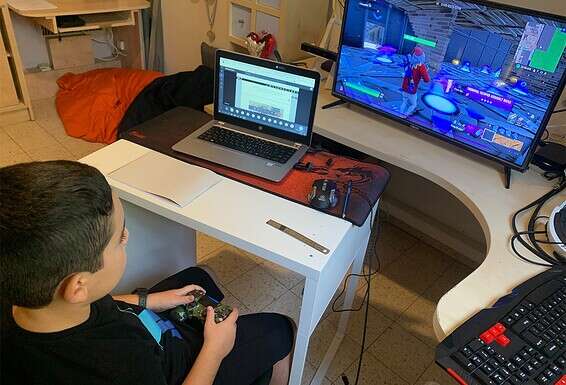 עין אחת לומדת, עין שנייה משחקת. רותם (9) בשיעור בזום // צילום: עמי שומן